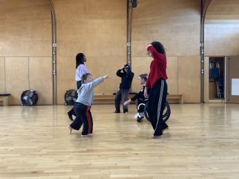 Five people dancing in a big, bright studio space.